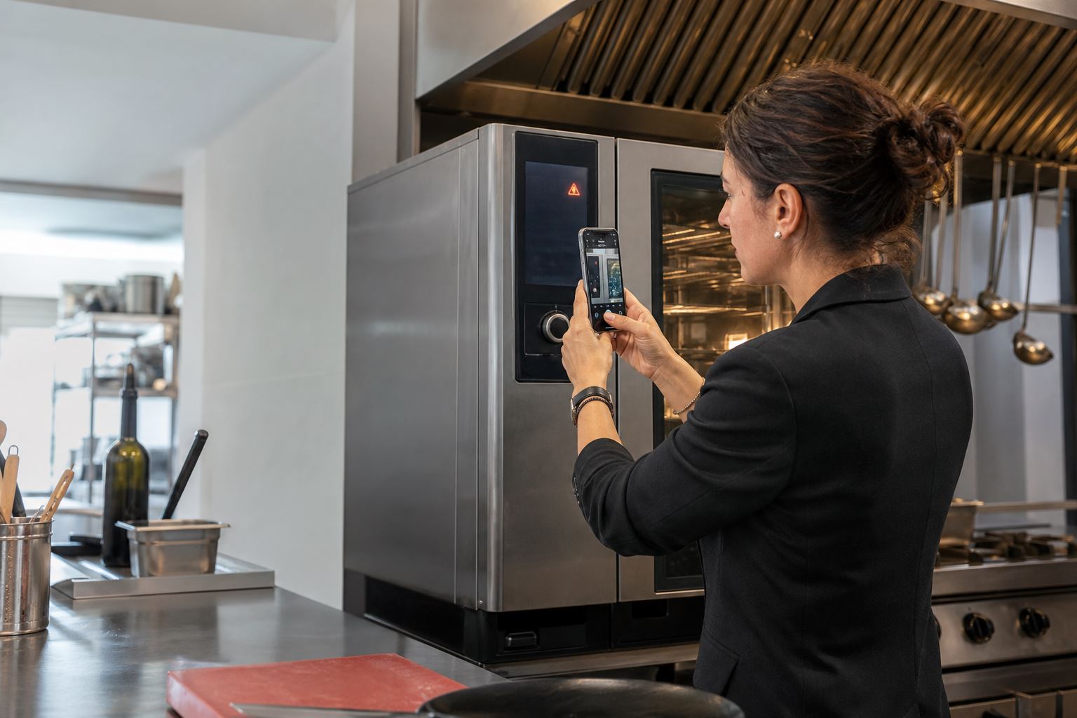 Una encargada fotografía con su móvil el aviso de error en el panel de un horno de cocina profesional